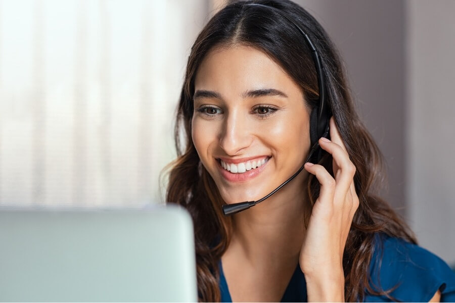 A woman wearing a microphone headset looking at a computer screen