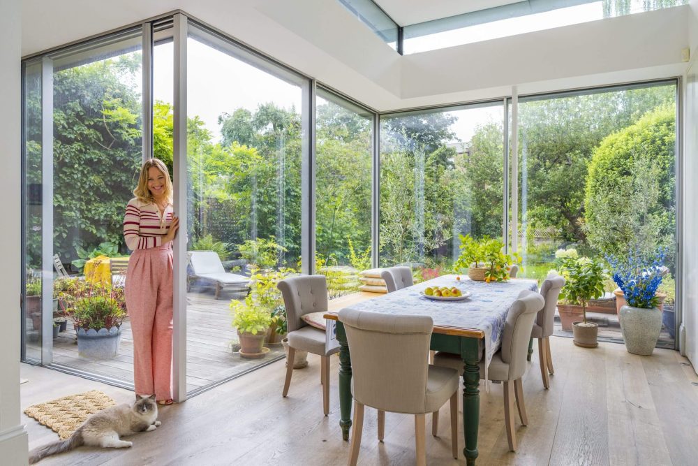 A person with their cat standing next to a dining table