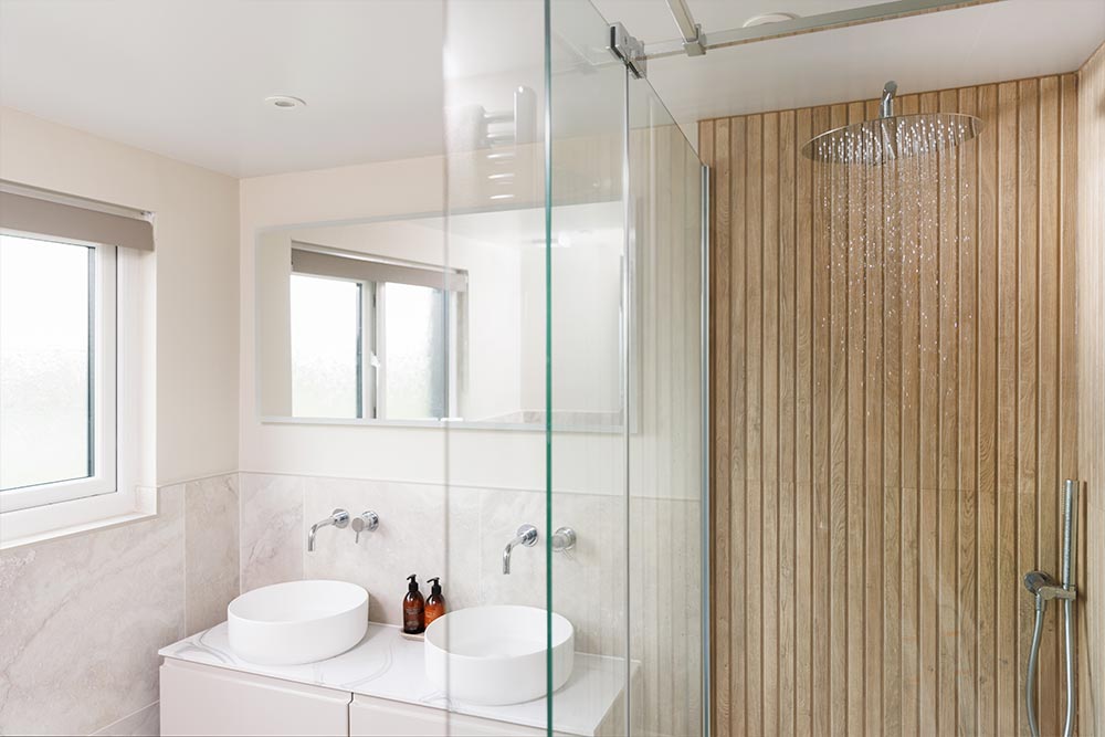 A drench shower head set up in a bathroom with two sinks