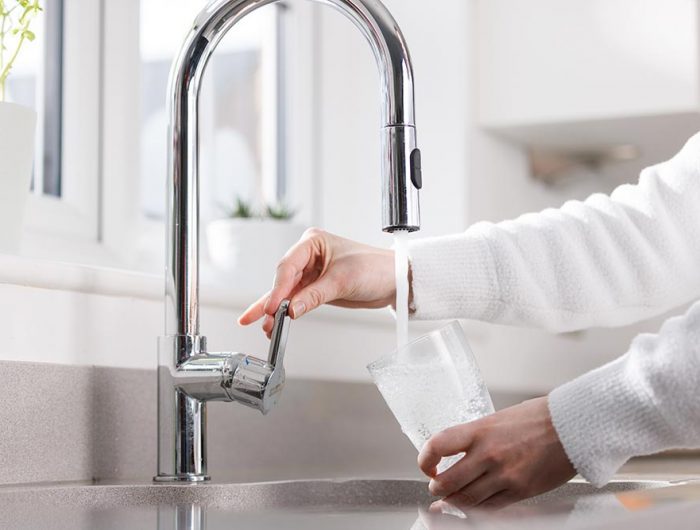 Someone filling up a glass using a kitchen sink