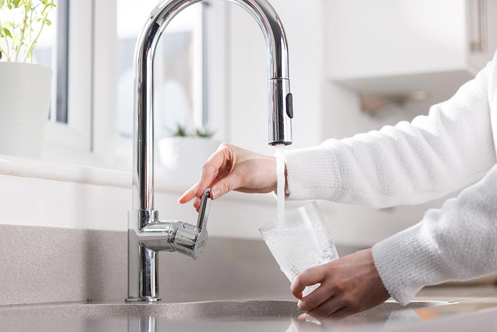 Someone filling up a glass using a kitchen sink