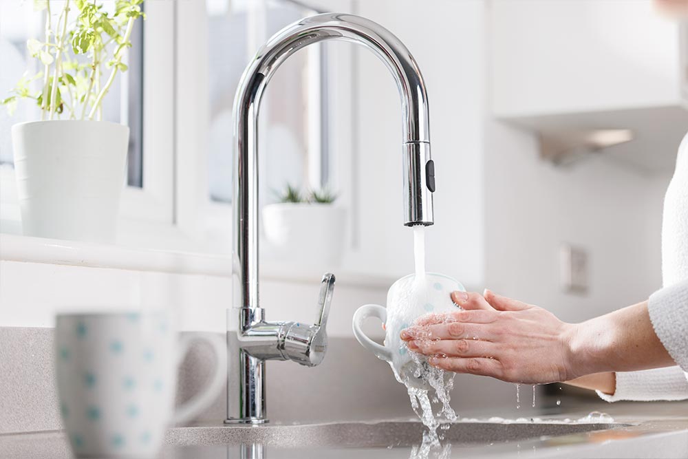 Someone washing a mug with a powerful kitchen tap