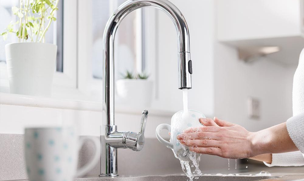 Someone washing a mug with a powerful kitchen tap